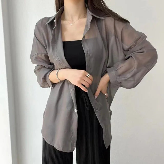 Sheer gray button up lightweight sun protection shirt worn over black tank with long sleeves