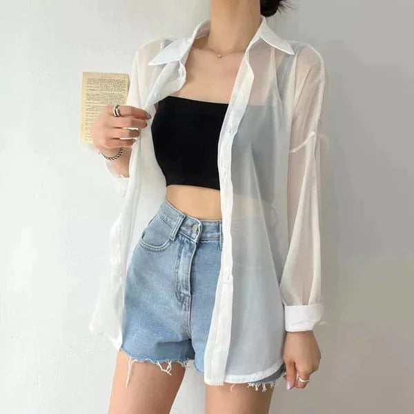 Sheer white button front lightweight sun protection shirt worn open over black crop top and denim shorts