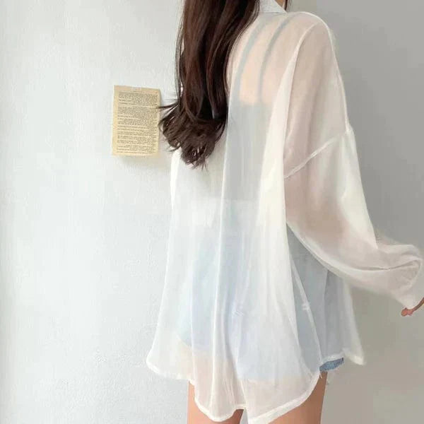 Back view of woman wearing sheer white lightweight sun protection shirt with relaxed flowy fit