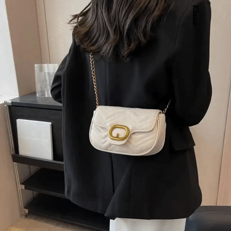 Woman in black blazer wearing a cream quilted shoulder bag with gold buckle chain strap luxury minimalist leather bag