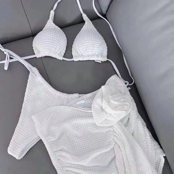 White textured triangle bikini and ruched floral coverup on gray sofa white beachwear set for women