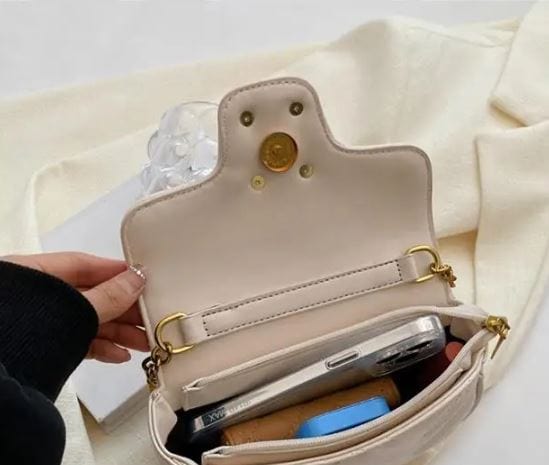Cream crossbody luxury minimalist leather bag open showing phone wallet and gold hardware interior pocket