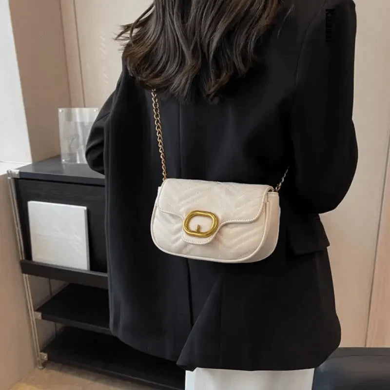 Woman in black blazer wearing a cream quilted shoulder bag with gold buckle chain strap luxury minimalist leather bag