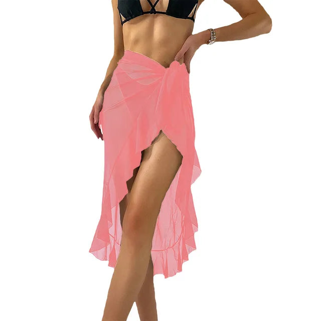 Pink sheer summer beach wrap skirt with high side slit and ruffle hem worn over black bikini for beach vacation