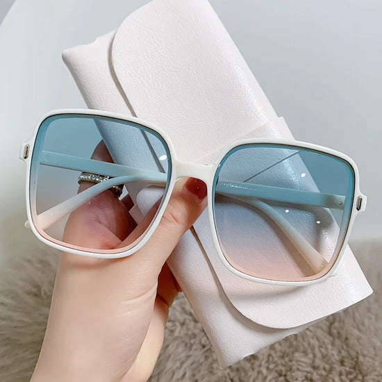 White oversized square sunglasses with blue gradient lenses held against white leather case summer breeze sunglasses deal